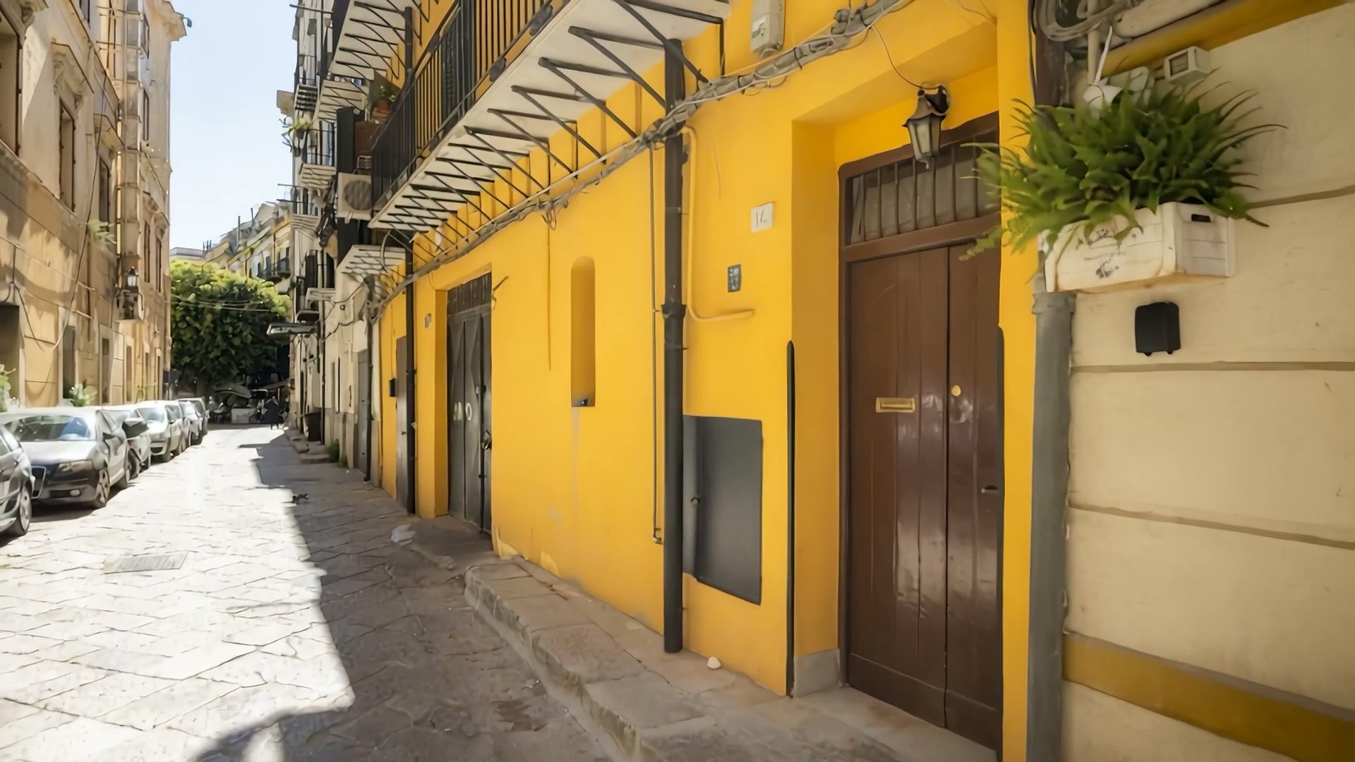 Il vicolo lastricato e la facciata gialla del palazzo