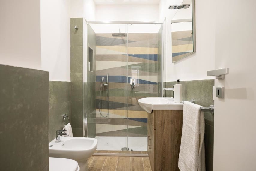 Il bagno con la doccia in vetro e il mobile in legno
